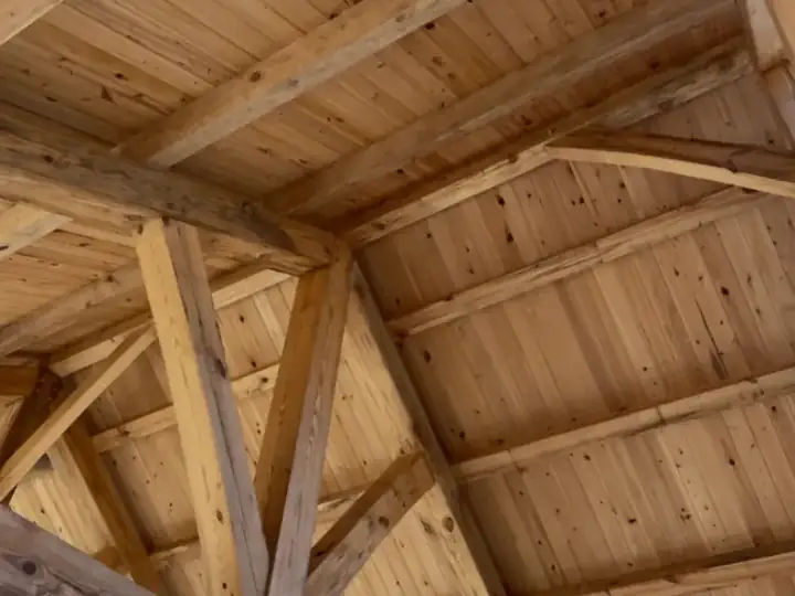 Angled view of heavy timber framing and wood ceiling boards