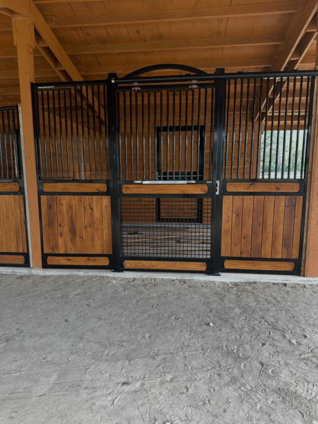 Horse stall front with wood infill panels and black steel framing