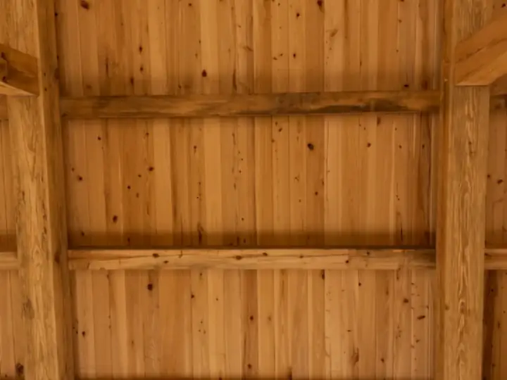 Timber-frame ceiling panel with warm wood boards and purlins