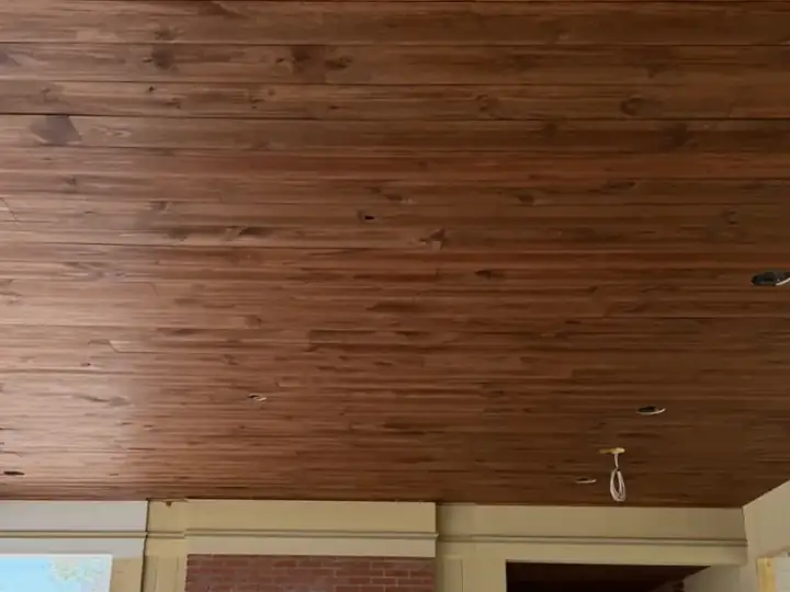 Large finished wood ceiling over a brick fireplace