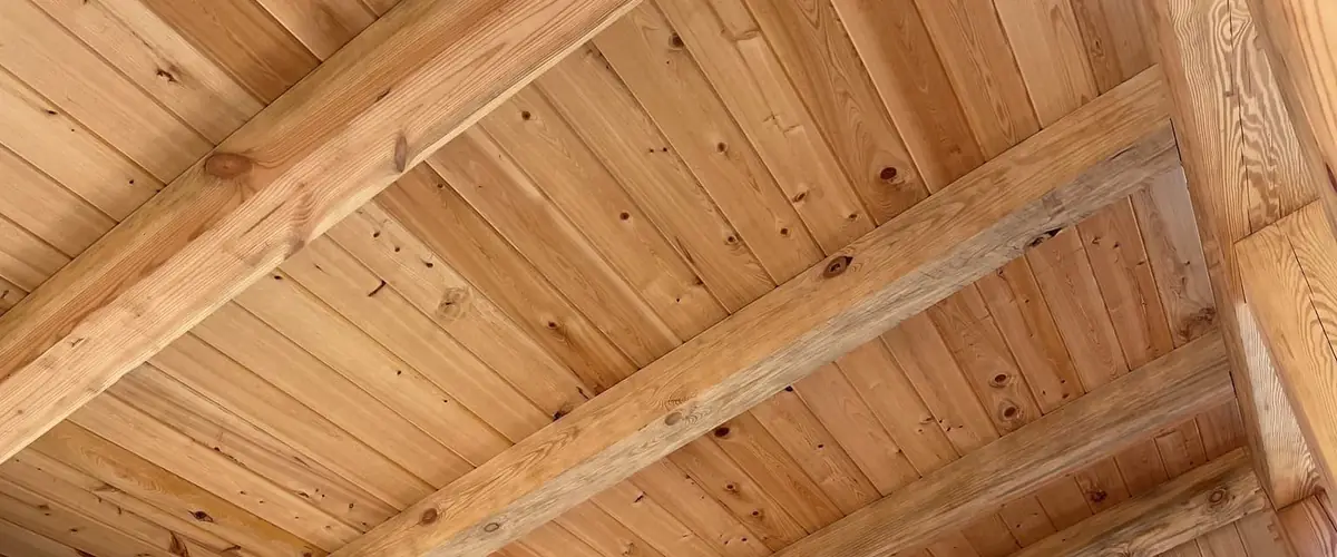 Pine tongue and groove ceiling in an open outdoor pavilion with exposed beams